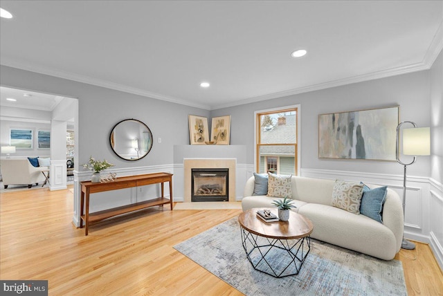 living room featuring a tiled fireplace, wood-type flooring, and ornamental molding