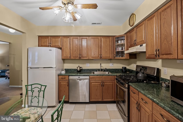 kitchen featuring appliances with stainless steel finishes, sink, ceiling fan, and dark stone counters