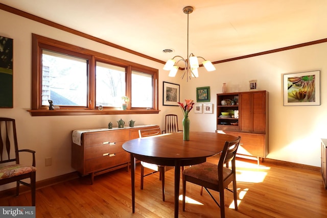 dining space featuring crown molding, a notable chandelier, and light hardwood / wood-style flooring