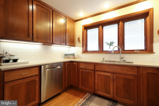 kitchen featuring sink, light stone counters, tasteful backsplash, stainless steel dishwasher, and light hardwood / wood-style floors