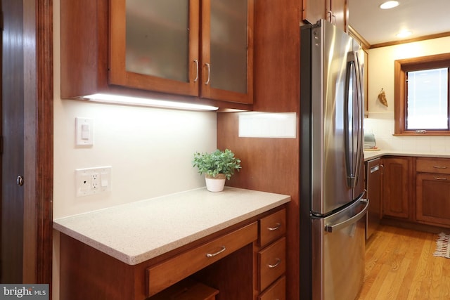 kitchen with tasteful backsplash, crown molding, stainless steel fridge, and light hardwood / wood-style floors