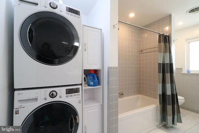 washroom with stacked washer and clothes dryer, tile walls, and light tile patterned floors