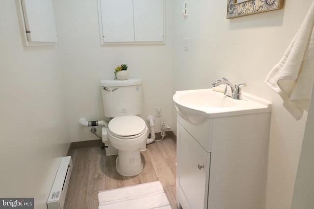 bathroom featuring hardwood / wood-style flooring, vanity, toilet, and a baseboard heating unit