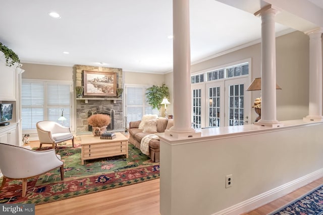 living room with decorative columns, crown molding, and light wood-type flooring