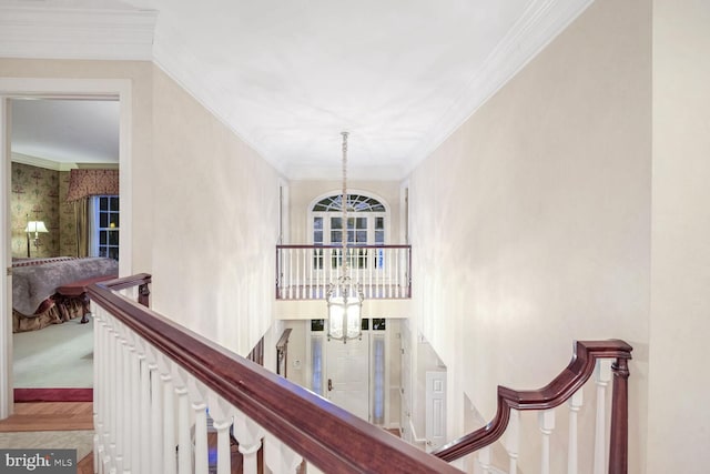 hallway with a notable chandelier, ornamental molding, and carpet flooring