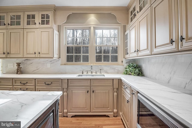 kitchen with tasteful backsplash, sink, light stone countertops, and light wood-type flooring