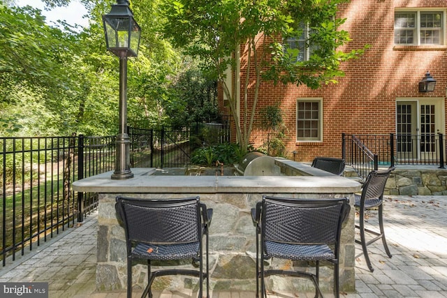 view of patio / terrace featuring a bar and exterior kitchen