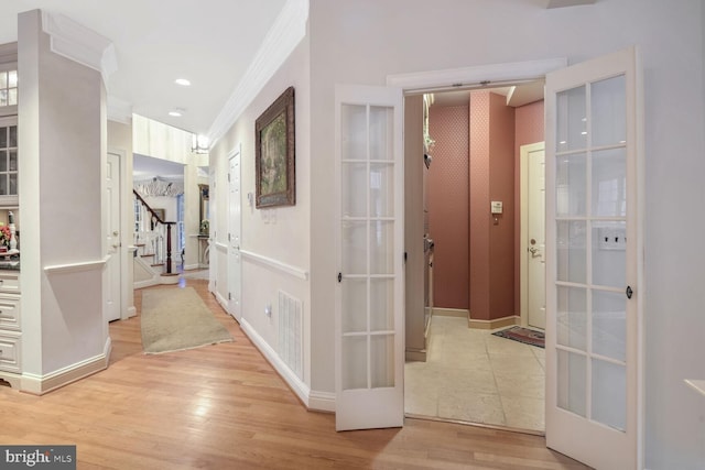 corridor featuring french doors, crown molding, and light hardwood / wood-style flooring