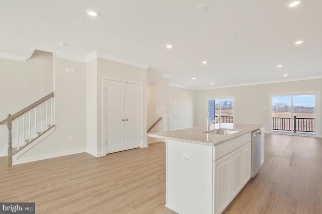 kitchen with white cabinetry, sink, a kitchen island with sink, stainless steel dishwasher, and light hardwood / wood-style floors