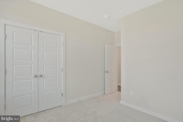 unfurnished bedroom with light carpet and a closet