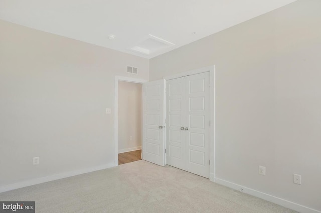 unfurnished bedroom with light carpet and a closet