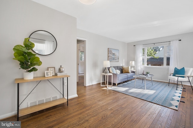 living area with visible vents, baseboards, and hardwood / wood-style flooring