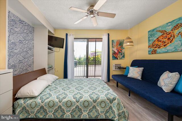 bedroom with ceiling fan, light hardwood / wood-style flooring, a textured ceiling, and access to outside