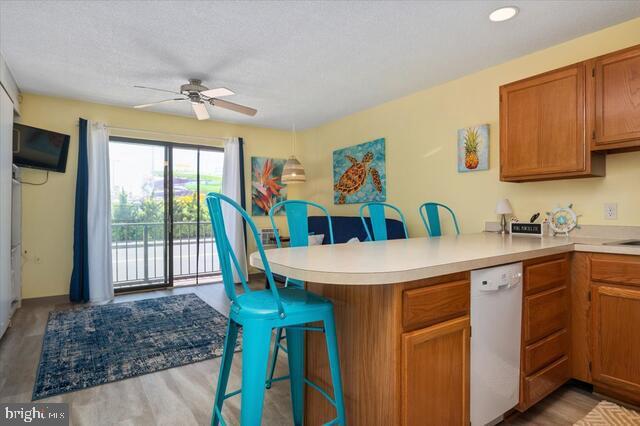 kitchen featuring hardwood / wood-style floors, dishwasher, a breakfast bar area, ceiling fan, and kitchen peninsula