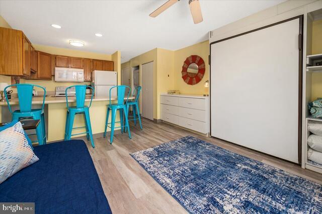 bedroom with light hardwood / wood-style floors and white refrigerator