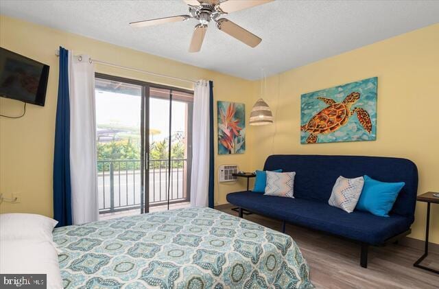 bedroom with a wall mounted air conditioner, a textured ceiling, access to outside, ceiling fan, and hardwood / wood-style floors