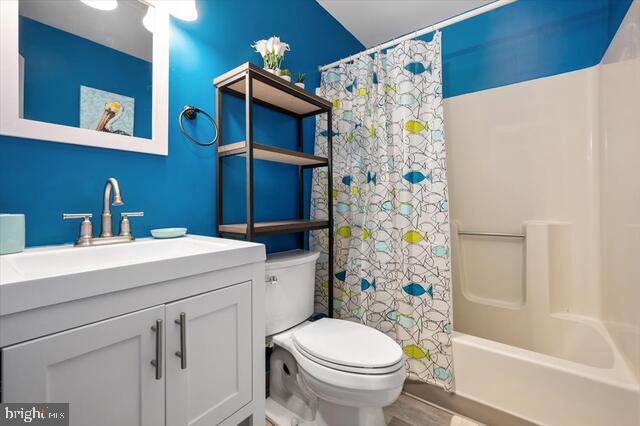 full bathroom with shower / tub combo, vanity, hardwood / wood-style flooring, and toilet