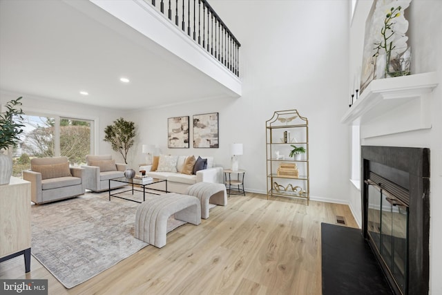 living room featuring a towering ceiling and light hardwood / wood-style flooring