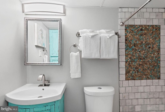 bathroom featuring toilet, sink, and a tile shower