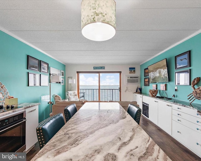 dining space with ornamental molding, dark hardwood / wood-style floors, a textured ceiling, and a wall unit AC