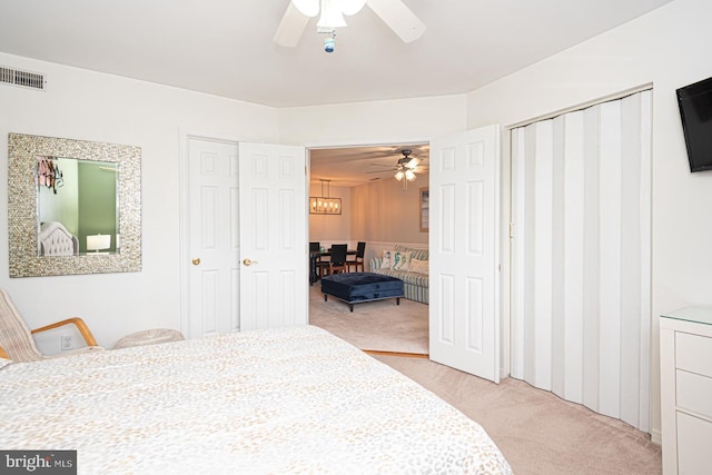 bedroom with two closets, light colored carpet, and ceiling fan