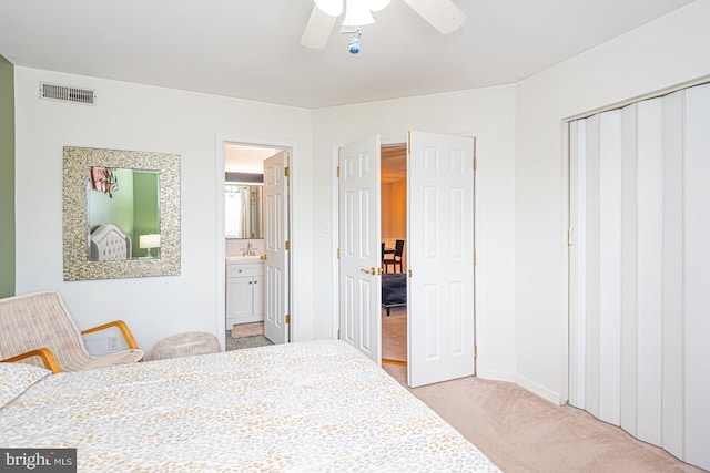 bedroom featuring sink, ensuite bath, light carpet, a closet, and ceiling fan