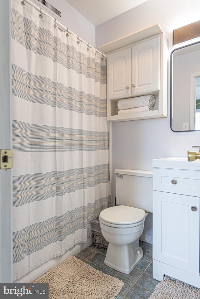 bathroom featuring vanity, curtained shower, and toilet