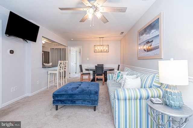 carpeted living room featuring ceiling fan with notable chandelier