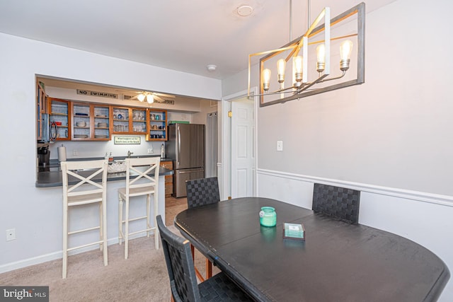 carpeted dining area featuring ceiling fan with notable chandelier