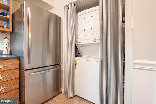 laundry area featuring light tile patterned flooring and stacked washer / drying machine