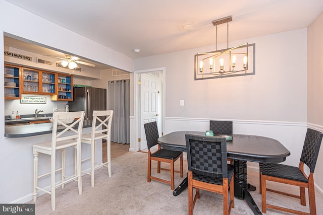 carpeted dining space featuring sink and ceiling fan with notable chandelier