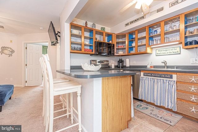 kitchen with sink, ceiling fan, appliances with stainless steel finishes, a kitchen bar, and kitchen peninsula