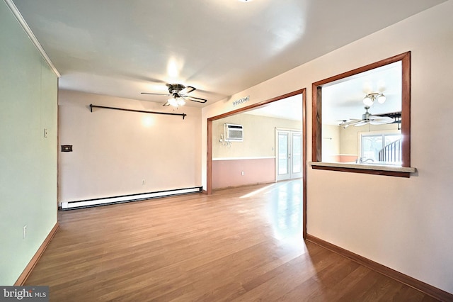 unfurnished room featuring baseboard heating, ceiling fan, wood-type flooring, and a wall mounted air conditioner