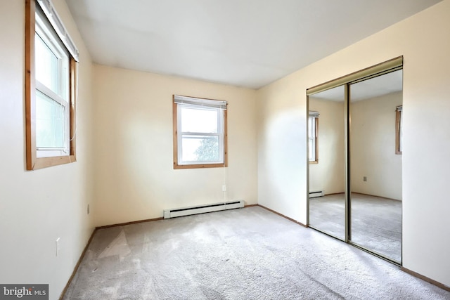 unfurnished bedroom with light colored carpet, a closet, and a baseboard heating unit