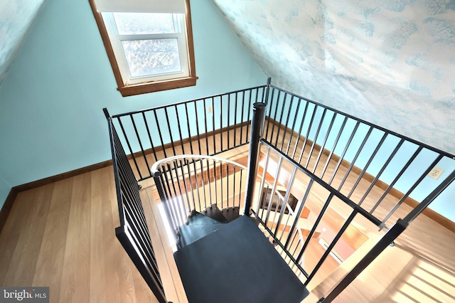 stairs featuring wood-type flooring and lofted ceiling