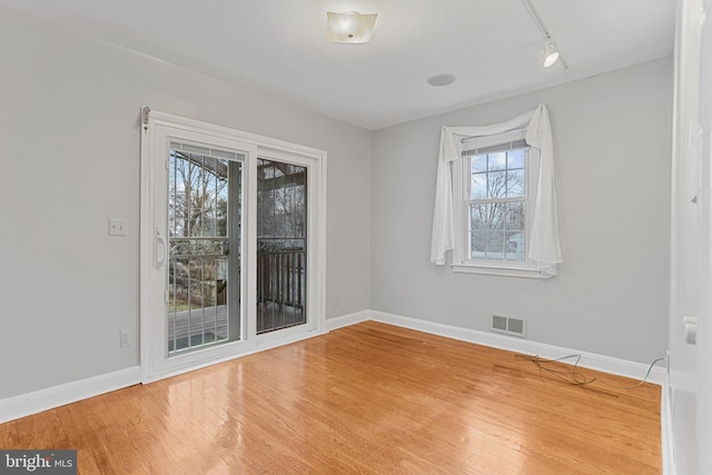 spare room with track lighting and hardwood / wood-style floors