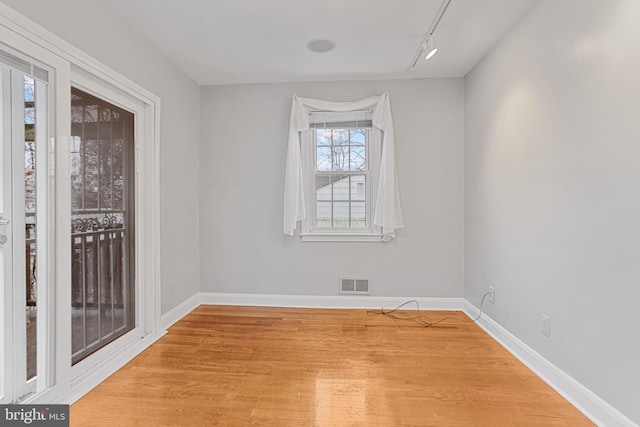 empty room featuring track lighting and light wood-type flooring