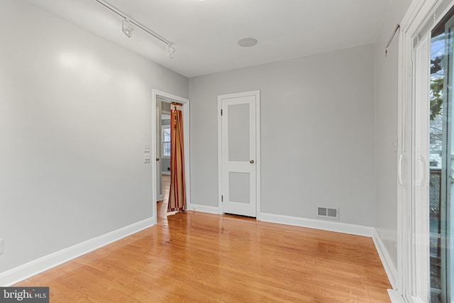 empty room featuring light hardwood / wood-style flooring and track lighting