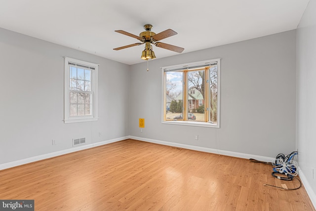 unfurnished room featuring ceiling fan, a wealth of natural light, and light wood-type flooring