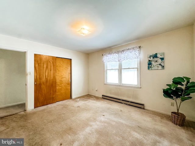 unfurnished bedroom with a baseboard heating unit, a closet, light carpet, and baseboards