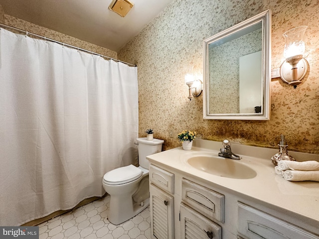 full bath with toilet, vanity, and wallpapered walls