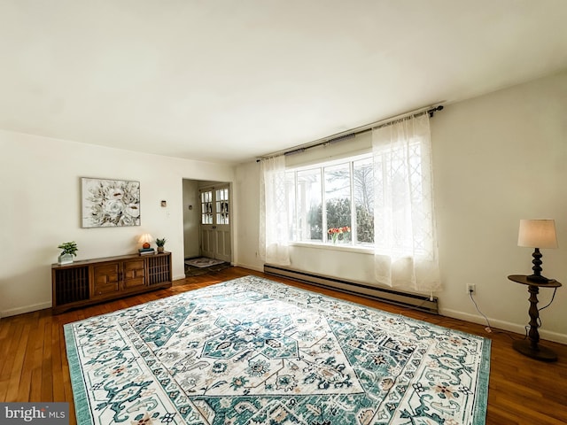 interior space with a baseboard heating unit, dark wood-style flooring, and baseboards