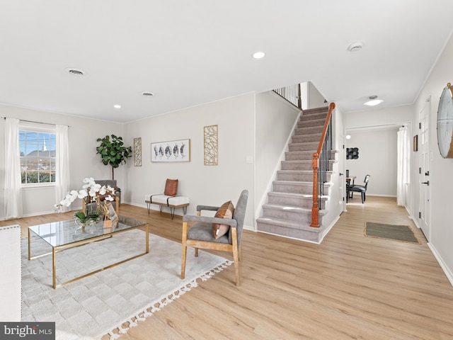 living room featuring crown molding and light hardwood / wood-style flooring