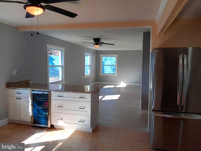 kitchen with light stone counters, wine cooler, light tile patterned flooring, white cabinets, and freestanding refrigerator