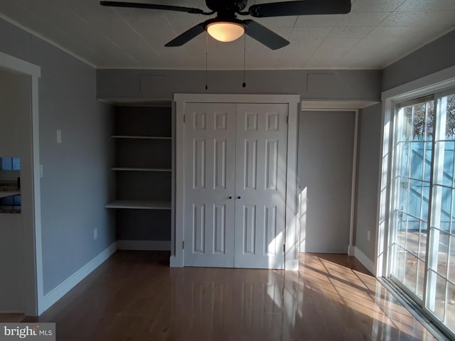 unfurnished bedroom with ceiling fan, wood finished floors, and baseboards