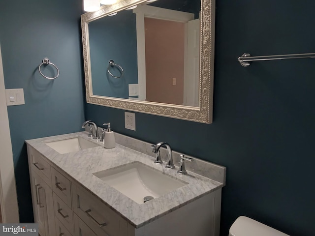 bathroom with double vanity, toilet, and a sink