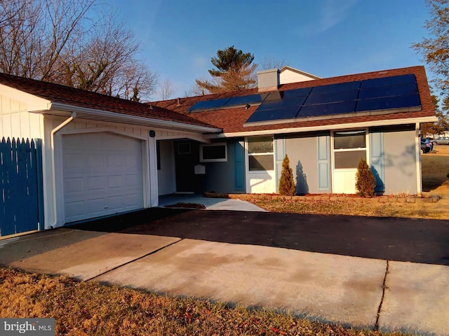 single story home featuring an attached garage, driveway, and solar panels