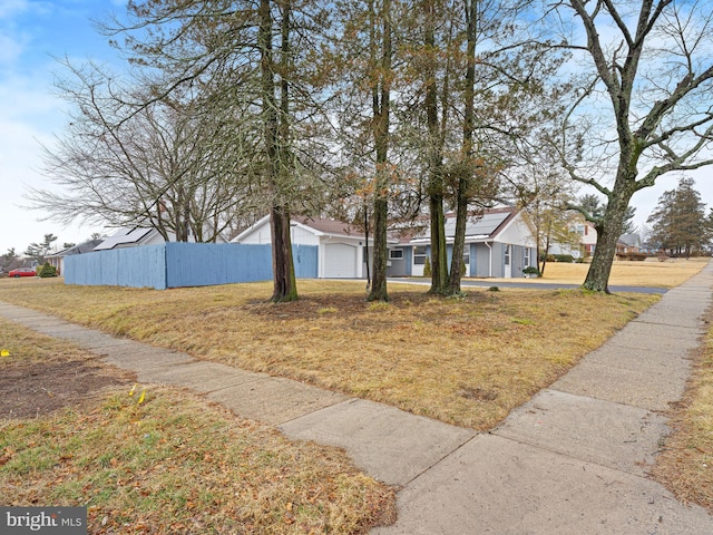 view of front of house featuring a garage, a front lawn, and fence