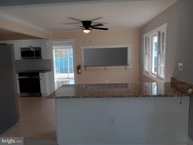 kitchen featuring a peninsula, appliances with stainless steel finishes, stone counters, and white cabinetry