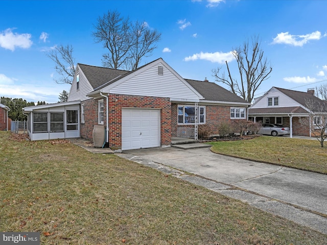 view of front of property featuring a garage, a sunroom, and a front lawn